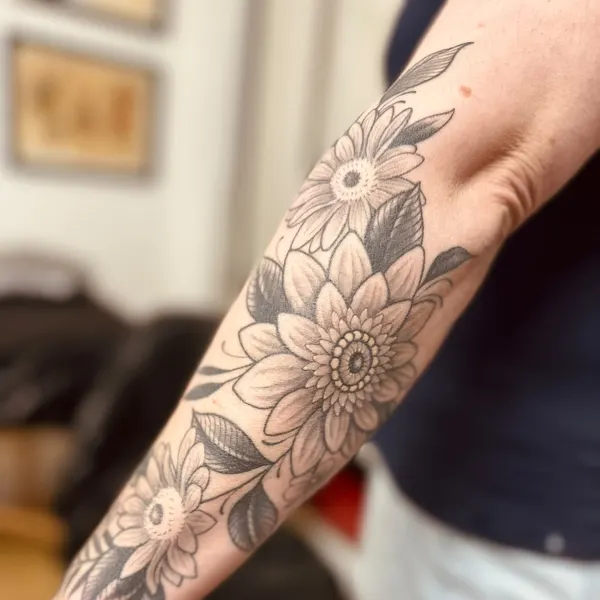black and grey chrysanthemums and daisies with dark leaves, forearm piece, by hannah at shade studio peterborough