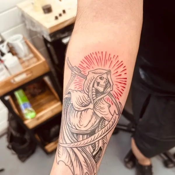 hooded skeletal reaper with a red rayed halo, medieval linework on the forearm, by hannah at shade studio peterborough